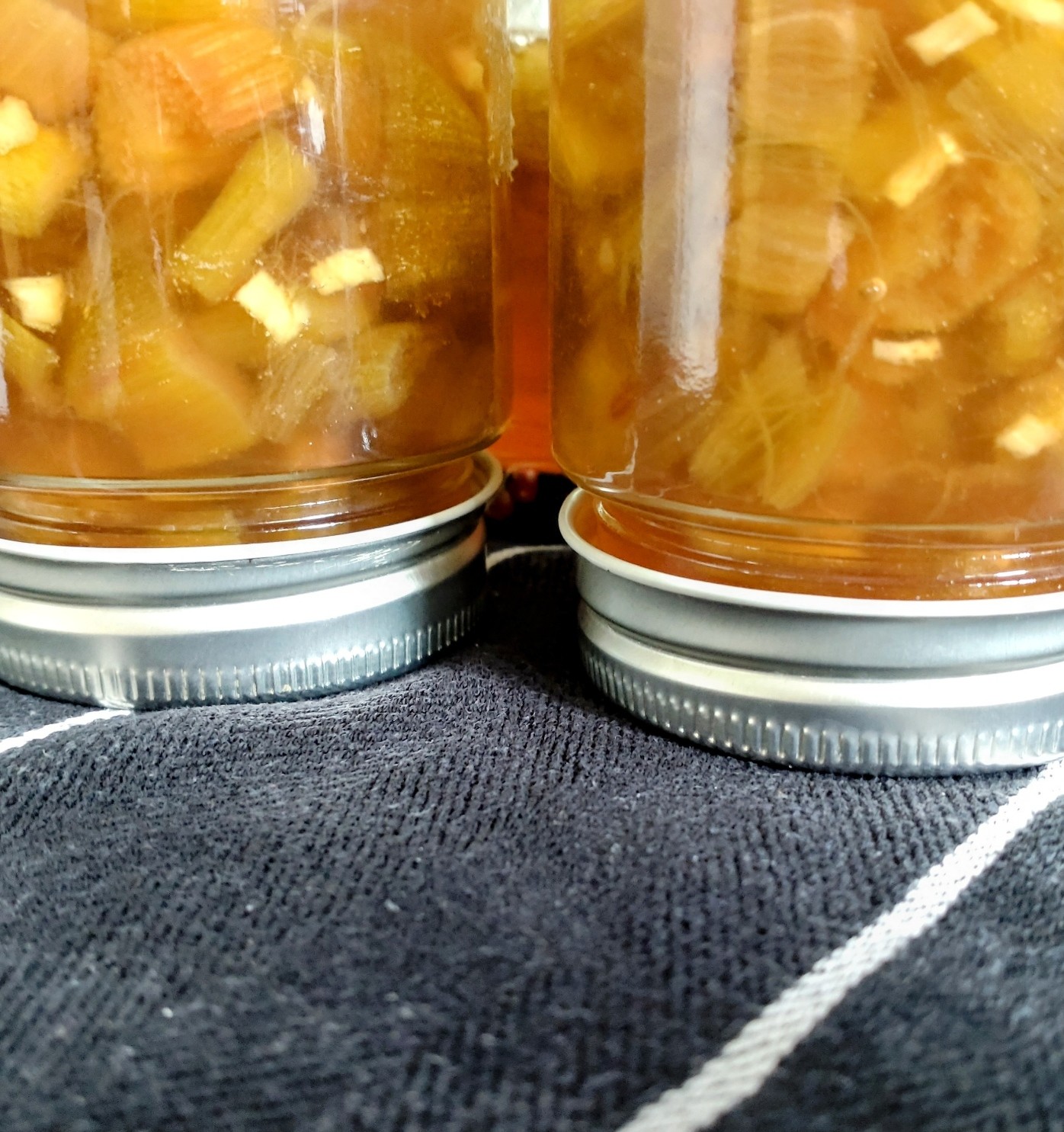 Tarros de mermelada puestos boca abajo sobre un paño de cocina para que las tapaderas sellen bien.