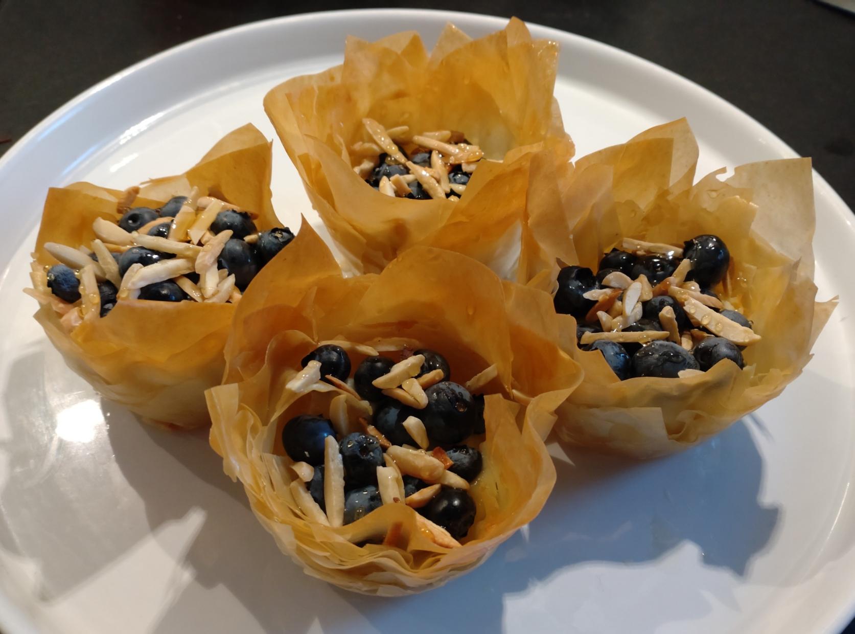 Cuatro trujas en un plato grande. Las trujas son, como todo el mundo sabe, unos dulces rurales, crujientes y empalagosos - con crema pastelera, arándanos, almendras tostadas y miel.