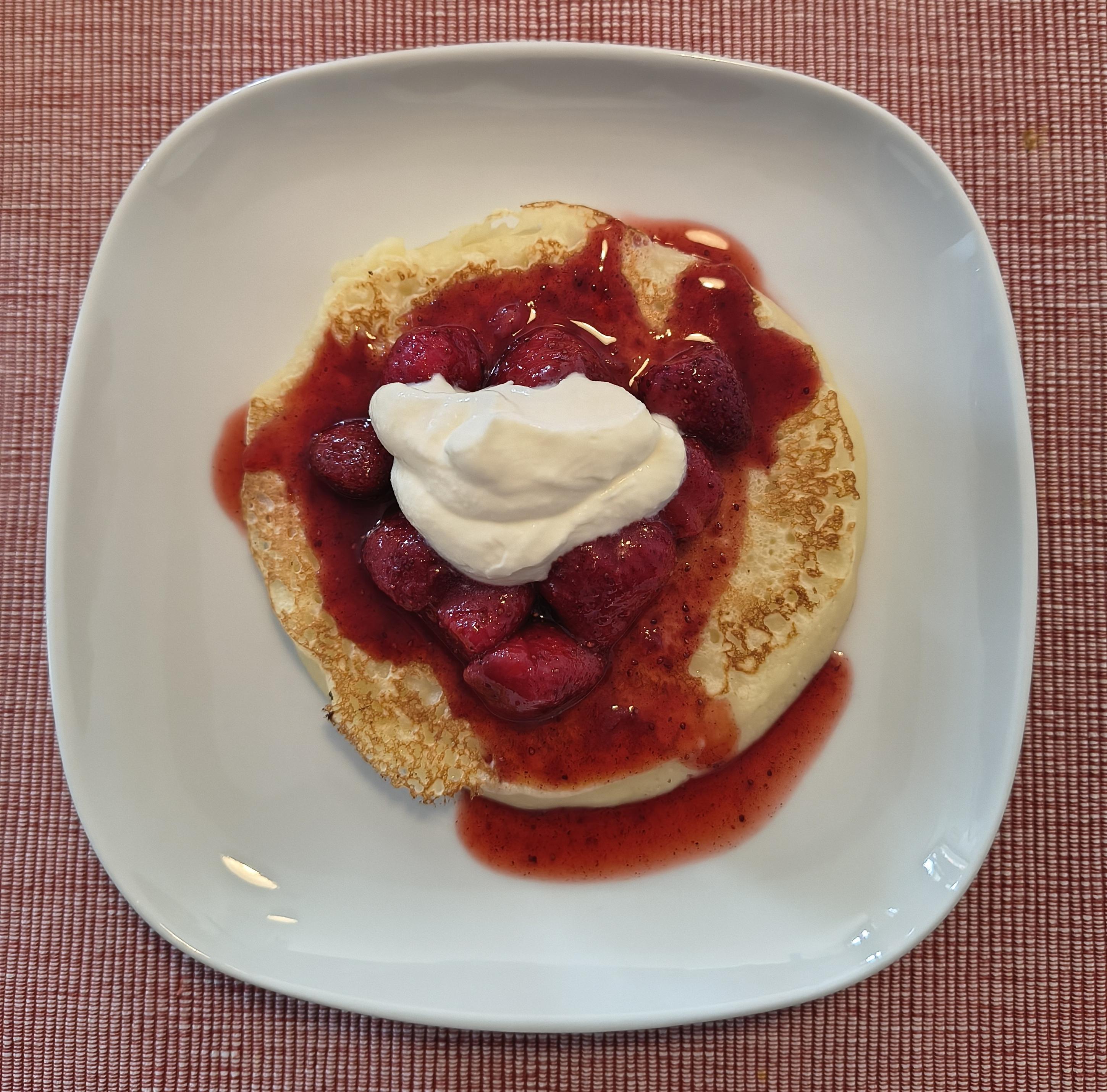 Plato con una tortita, compota de fresas y nata montada.