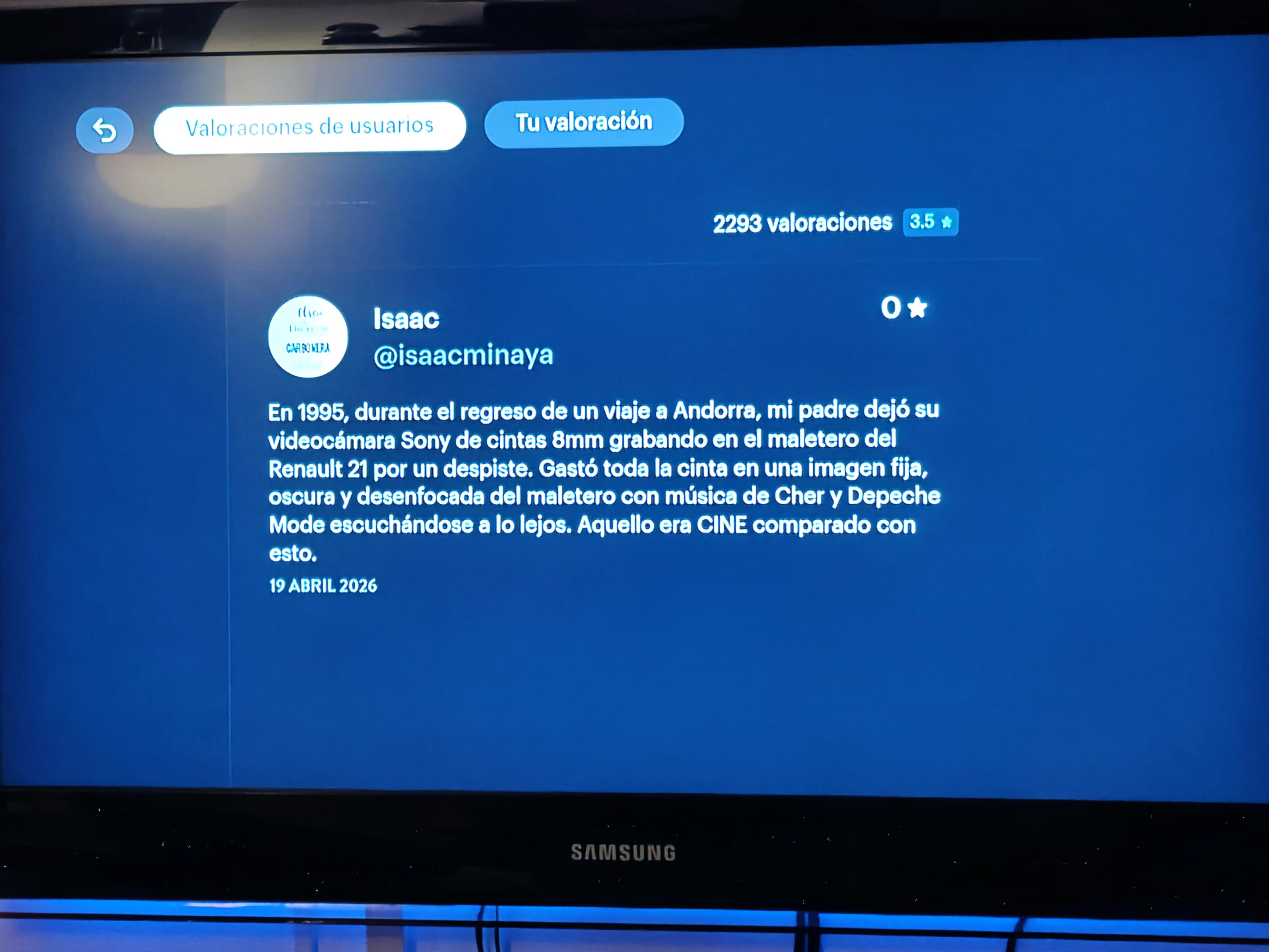 Pantalla de valoraciones de usuarios en un televisor. Aparece una reseña de Isaac, con cero estrellas: «En 1995, durante el regreso de un viaje a Andorra, mi padre dejó su videocámara Sony de cintas 8mm grabando en el maletero del Renault 21 por un despiste. Gastó toda la cinta en una imagen fija, oscura y desenfocada del maletero con música de Cher y Depeche Mode escuchándose a lo lejos. Aquello era CINE comparado con esto».